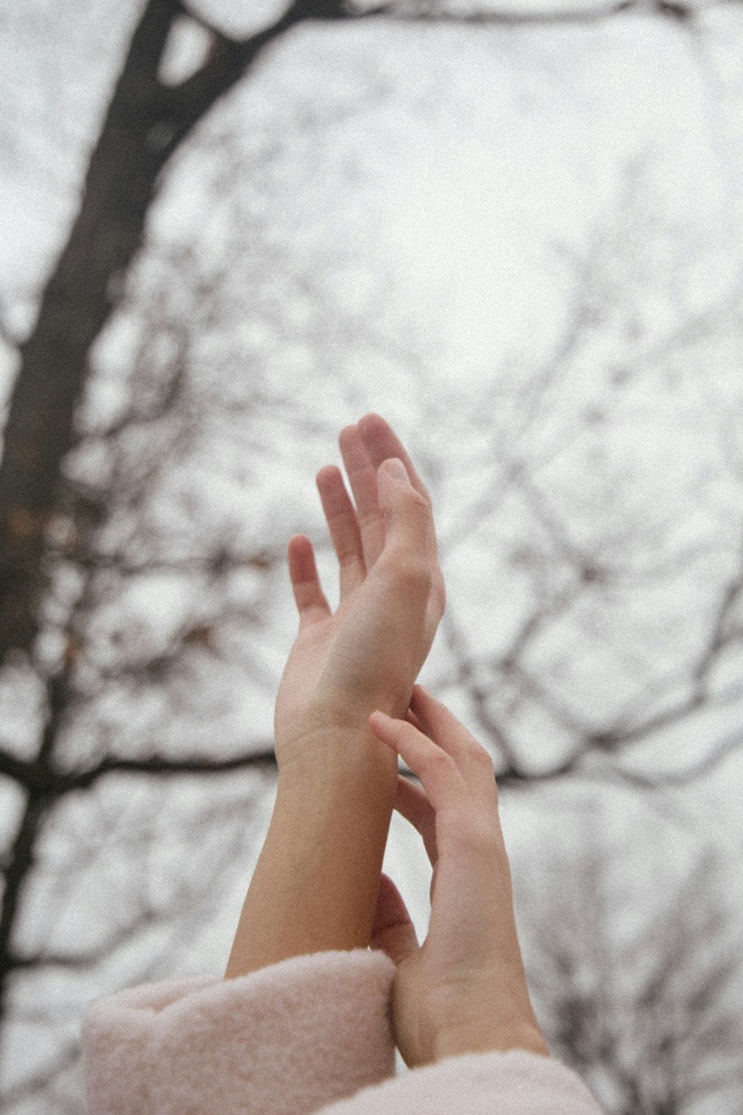 Hands hold a forearm while wearing a soft pink cuff.